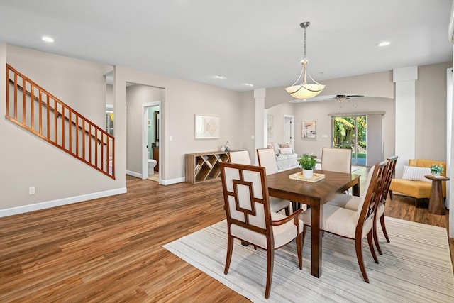 dining room featuring stairway, baseboards, light wood-style flooring, decorative columns, and ceiling fan