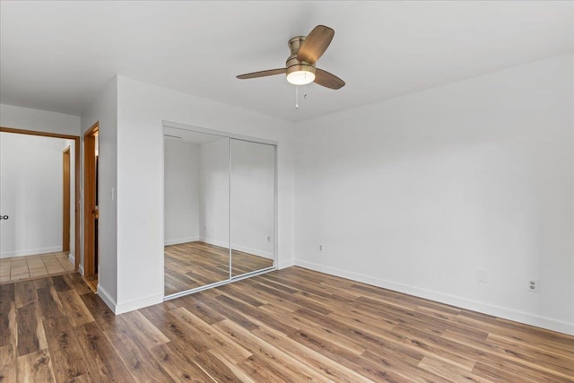 unfurnished bedroom featuring dark wood-type flooring, a closet, and ceiling fan