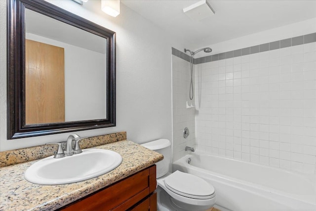 full bathroom featuring vanity, tiled shower / bath, and toilet