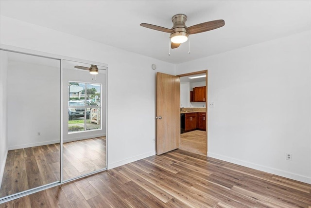 unfurnished bedroom featuring ceiling fan, light hardwood / wood-style floors, and a closet