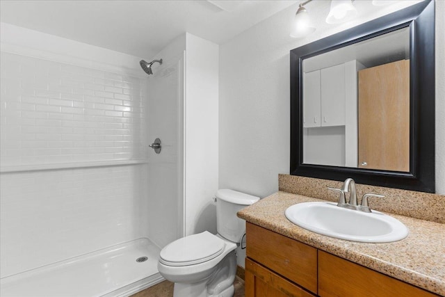 bathroom with vanity, toilet, and tiled shower