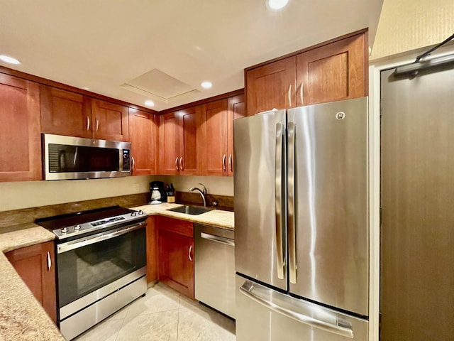 kitchen featuring light tile patterned floors, recessed lighting, a sink, appliances with stainless steel finishes, and brown cabinets