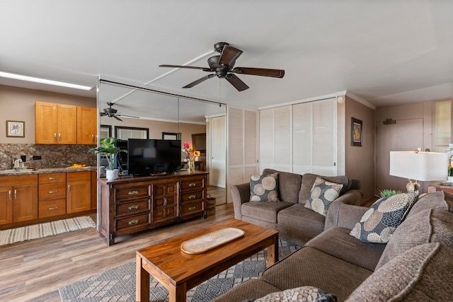 living room with ceiling fan, light hardwood / wood-style flooring, and sink