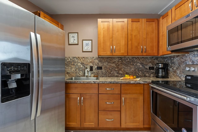 kitchen with sink, stainless steel appliances, dark stone counters, and tasteful backsplash