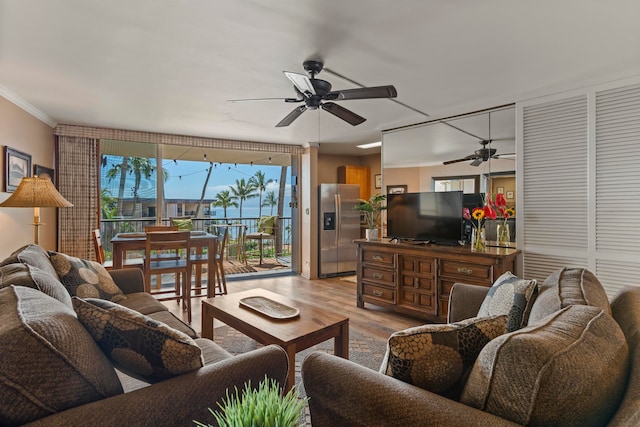 living room featuring light wood-type flooring, ceiling fan, and crown molding