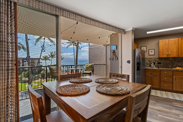 dining space with sink, a water view, and wood-type flooring