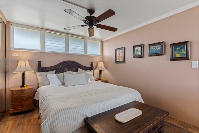 bedroom featuring multiple windows, dark hardwood / wood-style flooring, ceiling fan, and crown molding