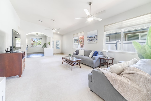 living room featuring ceiling fan, vaulted ceiling, light colored carpet, and arched walkways