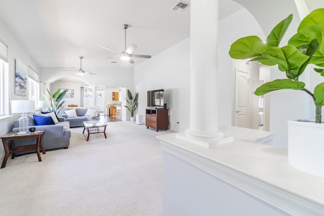 carpeted living room with ornate columns, arched walkways, ceiling fan, and lofted ceiling