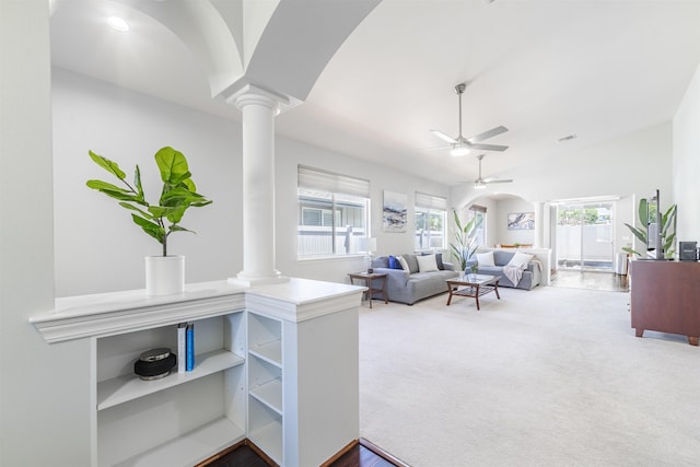 living room featuring ornate columns, ceiling fan, carpet, arched walkways, and vaulted ceiling