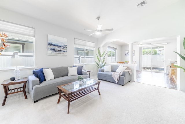 living area with a ceiling fan, arched walkways, light carpet, and decorative columns