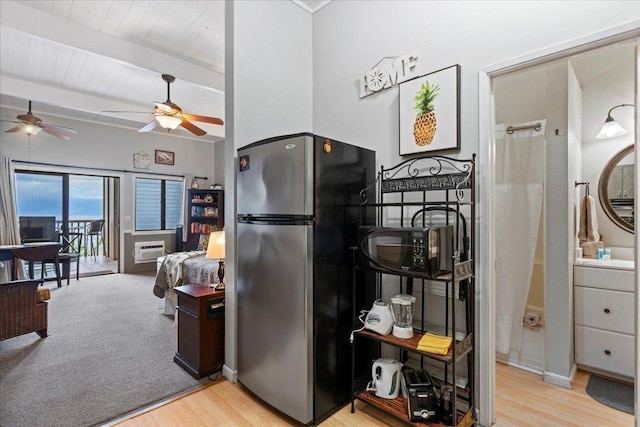 kitchen with beam ceiling, a wall mounted air conditioner, stainless steel refrigerator, and light hardwood / wood-style floors