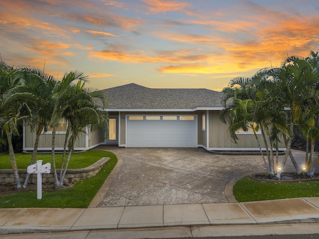 view of front of house with a front lawn, curved driveway, a garage, and roof with shingles
