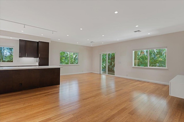 unfurnished living room featuring baseboards, light wood-style flooring, visible vents, and plenty of natural light