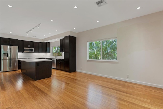 kitchen featuring light countertops, appliances with stainless steel finishes, a center island, light wood-type flooring, and visible vents