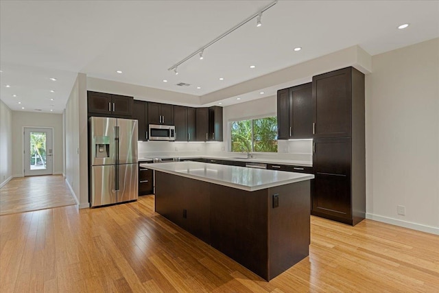 kitchen with light countertops, dark brown cabinetry, a center island, light wood-type flooring, and stainless steel appliances
