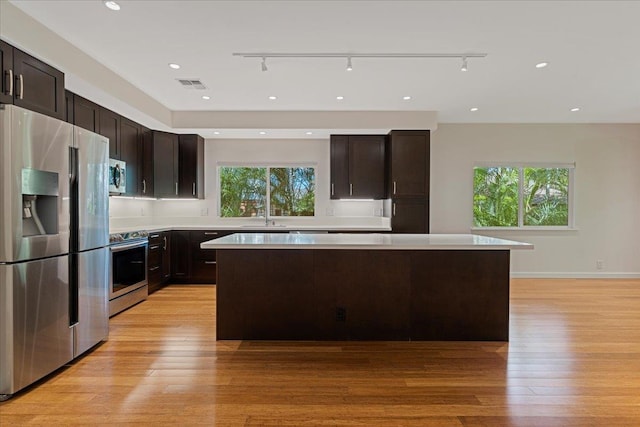 kitchen featuring a kitchen island, visible vents, light wood-style floors, and stainless steel appliances
