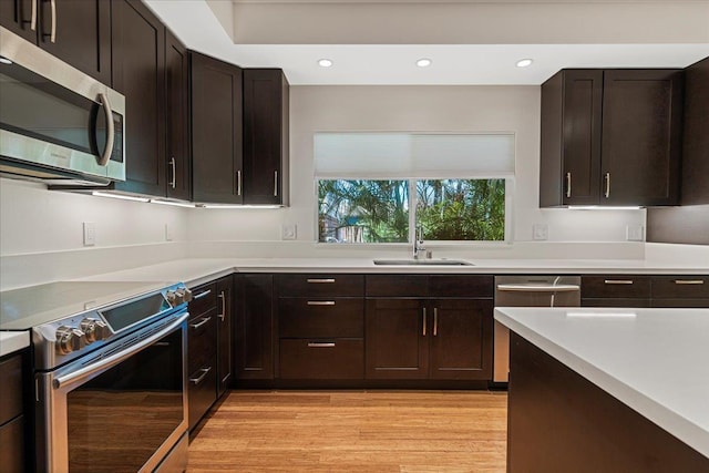 kitchen with light wood finished floors, a sink, light countertops, and appliances with stainless steel finishes