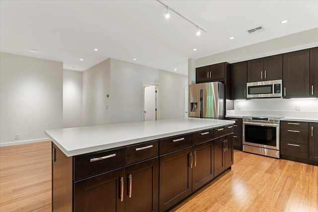 kitchen with light countertops, stainless steel appliances, a center island, light wood-style floors, and visible vents