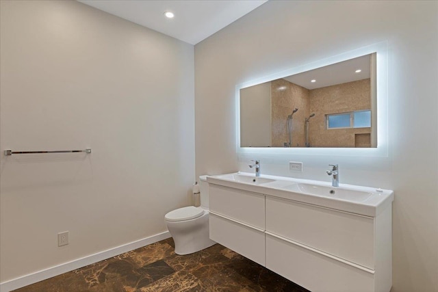 bathroom featuring baseboards, a sink, a tile shower, and toilet
