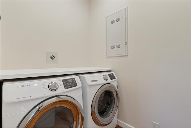 washroom featuring electric panel, washer and clothes dryer, and laundry area
