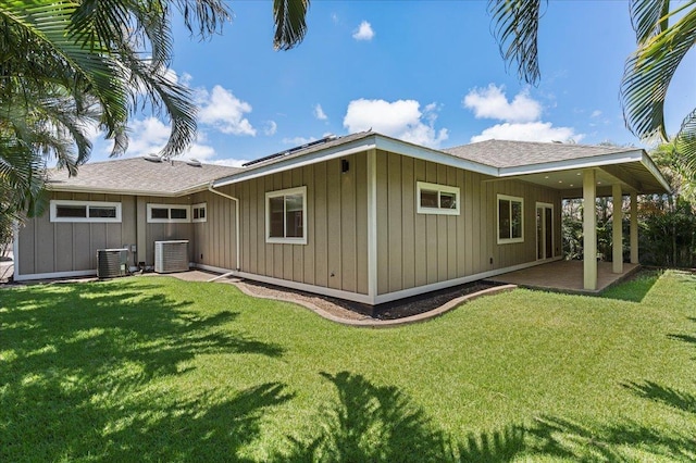back of property featuring central air condition unit, board and batten siding, a yard, and a patio area