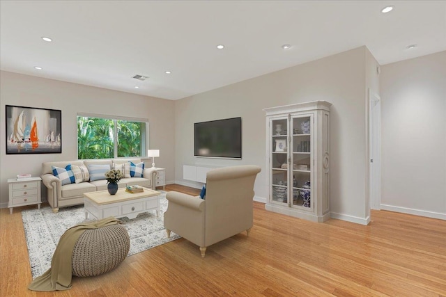 living room featuring baseboards, light wood-type flooring, visible vents, and recessed lighting