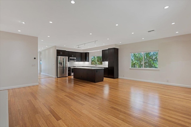 kitchen featuring open floor plan, a kitchen island, appliances with stainless steel finishes, and light wood finished floors
