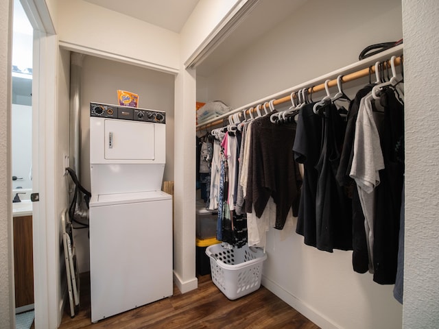 laundry area with dark hardwood / wood-style flooring and stacked washer and dryer