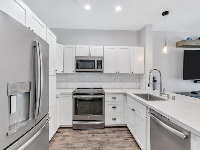 kitchen with pendant lighting, sink, white cabinets, and appliances with stainless steel finishes