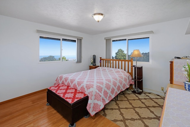 bedroom with light wood-type flooring and a textured ceiling