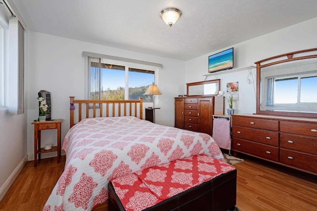 bedroom with dark hardwood / wood-style flooring and multiple windows