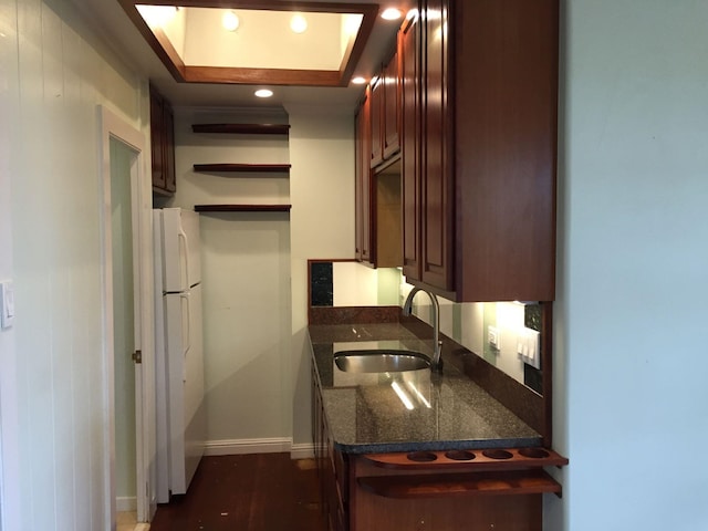 kitchen with dark wood-type flooring, a raised ceiling, sink, and white refrigerator