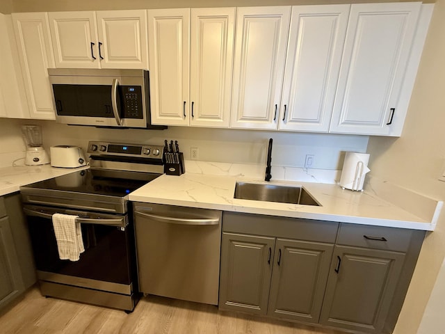 4327 Lower Honoapiilani Rd Unit 903B, Lahaina, HI 96761 - kitchen with white cabinets, light wood finished floors, a sink, gray cabinetry, and appliances with stainless steel finishes