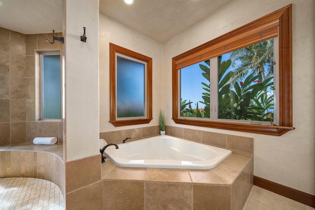 bathroom with tile patterned flooring, a wealth of natural light, and tiled tub