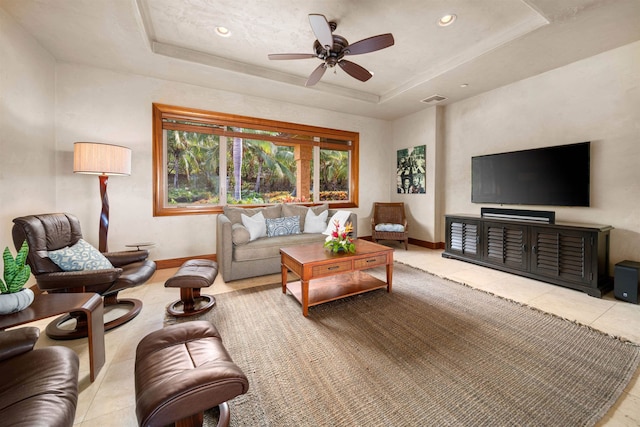 living room featuring light tile patterned floors, ceiling fan, and a raised ceiling