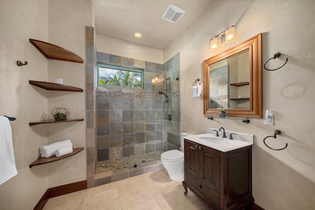 bathroom with tile patterned flooring, vanity, toilet, and tiled shower