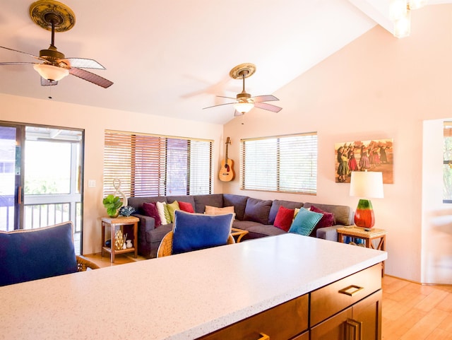 living area with lofted ceiling, ceiling fan, a wealth of natural light, and light wood-style floors