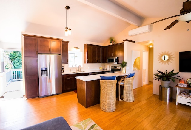 kitchen with light wood finished floors, appliances with stainless steel finishes, a wall mounted air conditioner, light countertops, and a sink