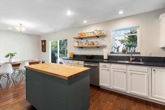 kitchen featuring butcher block countertops, dark wood-style flooring, dishwasher, a sink, and a center island
