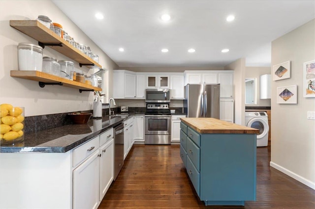 kitchen featuring a sink, appliances with stainless steel finishes, butcher block counters, washer / dryer, and white cabinets