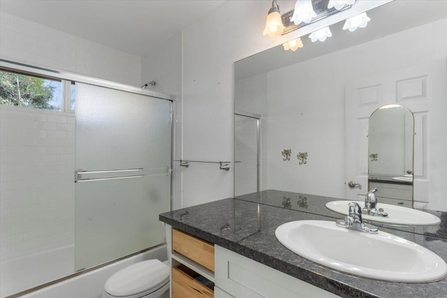 bathroom featuring toilet, vanity, and shower / bath combination with glass door