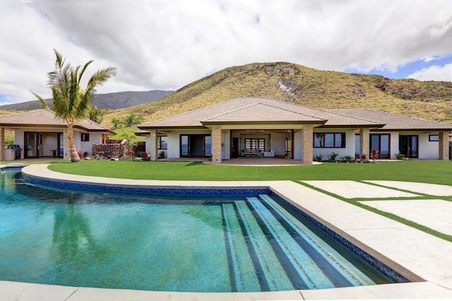 back of house featuring a patio area, a mountain view, and a yard