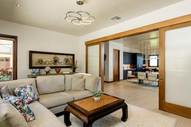 living room with a wealth of natural light, light hardwood / wood-style floors, and an inviting chandelier