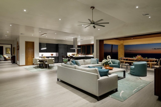 living room with ceiling fan, light hardwood / wood-style floors, and high vaulted ceiling