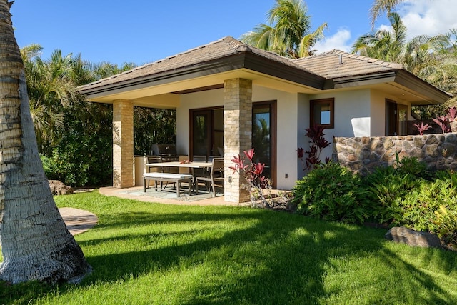 back of house with an outdoor kitchen, a patio area, and a yard