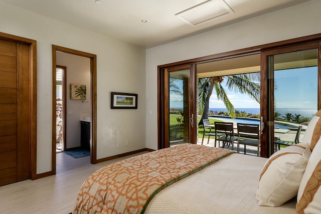 bedroom featuring light wood-type flooring, access to outside, and a water view