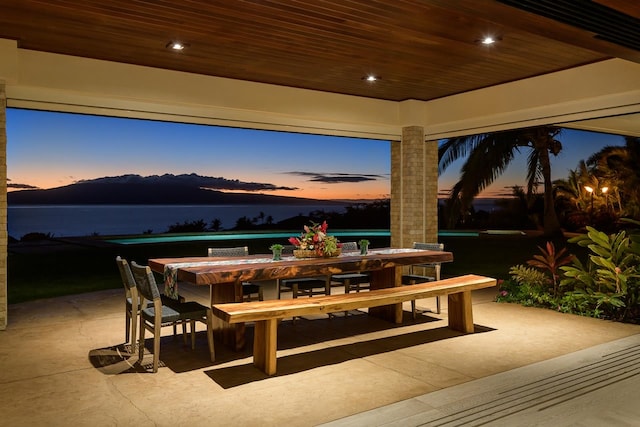 patio terrace at dusk with a water view and a bar