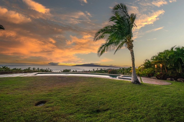 yard at dusk featuring a water view