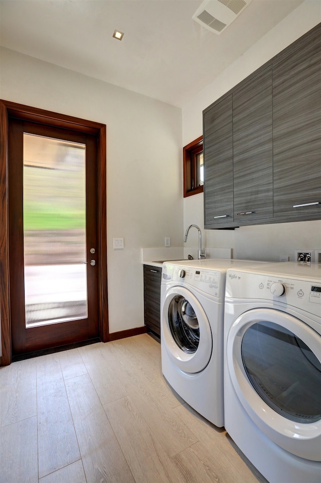 laundry room featuring sink, washer and clothes dryer, cabinets, and light wood-type flooring